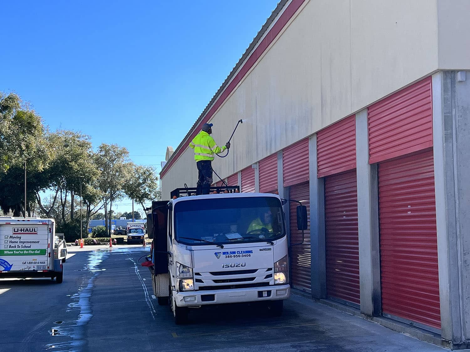 pressure washing professional washing storage unit building while standing on work truck