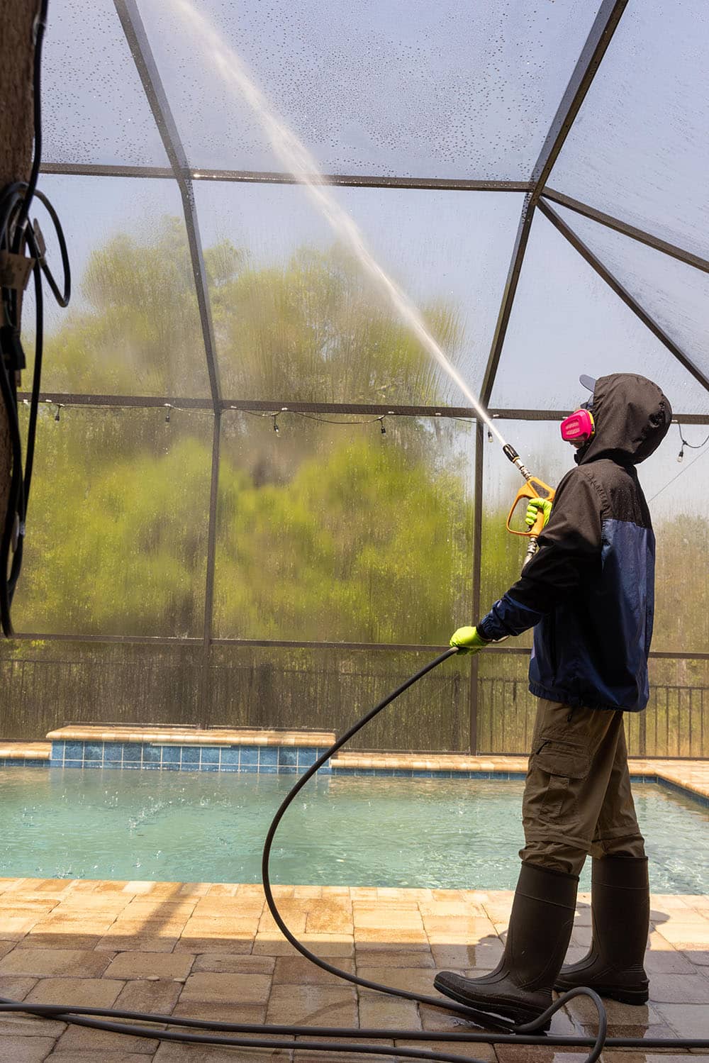 pressure washing professional spraying glass inside pool area